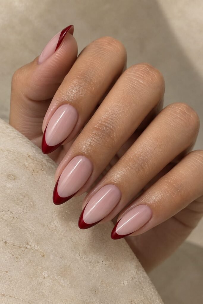 Almond nails with glossy cherry red French tips over a sheer pink base