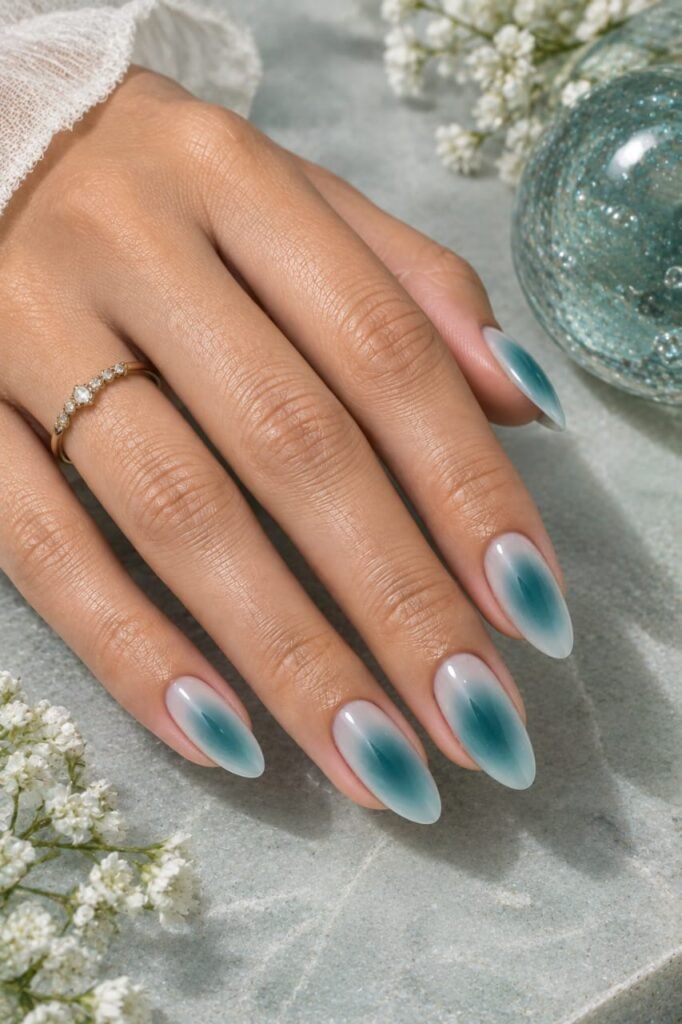 Almond teal aura nails with soft turquoise edges and diffused blue-green centers.