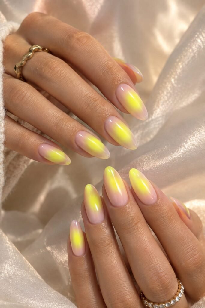 Electric yellow aura nails with glowing neon centers on long almond nails.