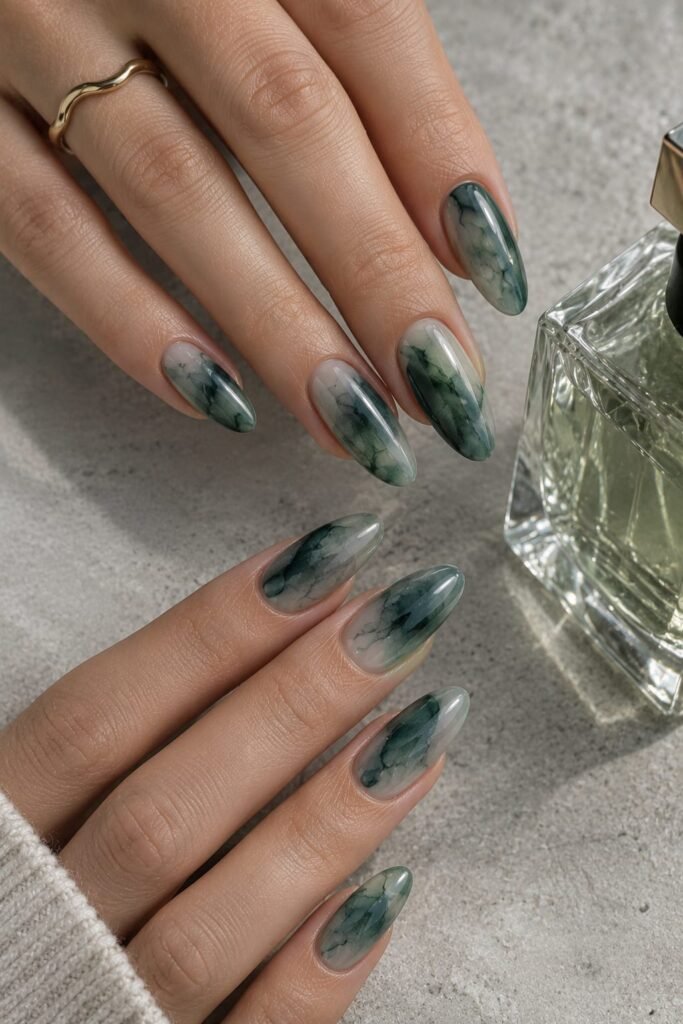 Long oval nails with translucent smoky jade and muted teal watercolor effects.