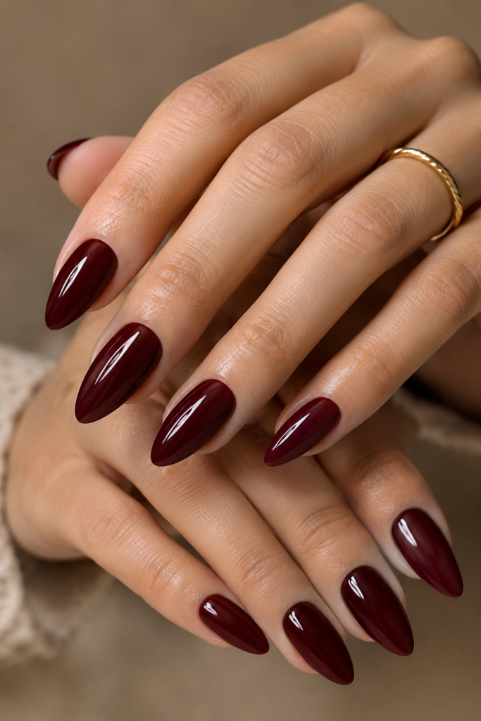 Medium almond nails in deep glossy burgundy with a luxurious glass-like finish.