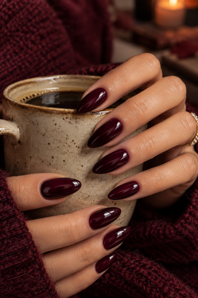 Medium almond nails painted in deep black cherry wine polish with an ultra-glossy finish.