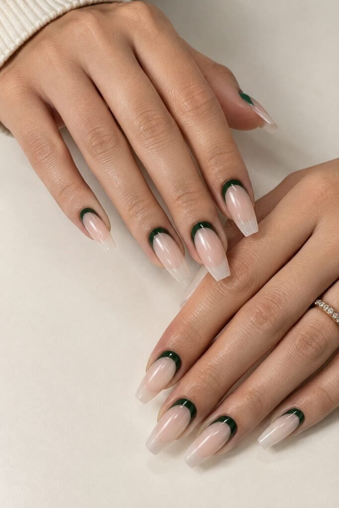 Medium coffin nails with sheer nude polish and deep green crescent details around the cuticles.
