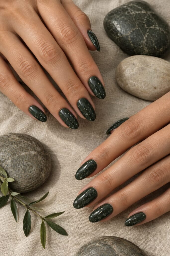 Medium oval midnight green nails with refined charcoal and ivory stone-inspired speckles.
