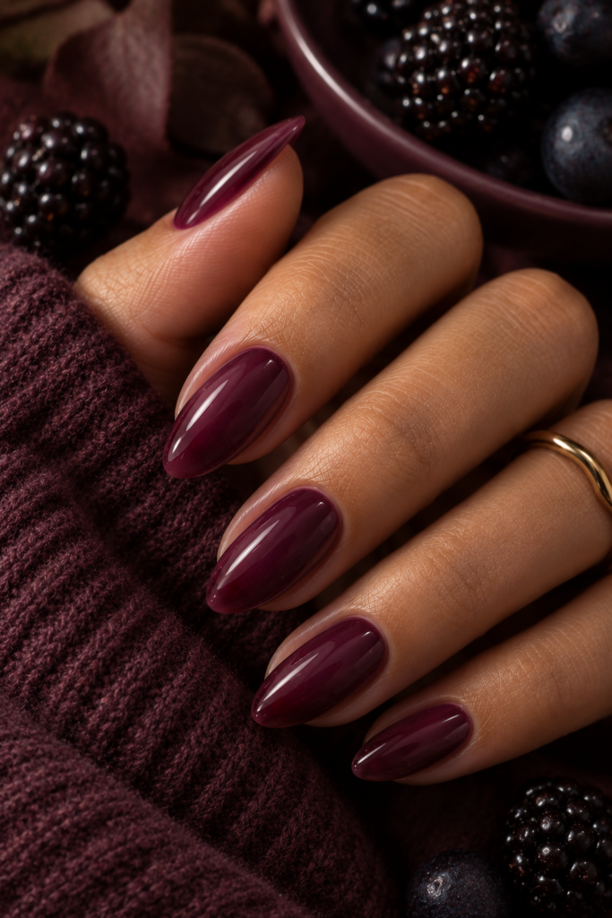 Medium oval nails painted in rich mulberry jelly polish with a glossy semi-sheer finish.