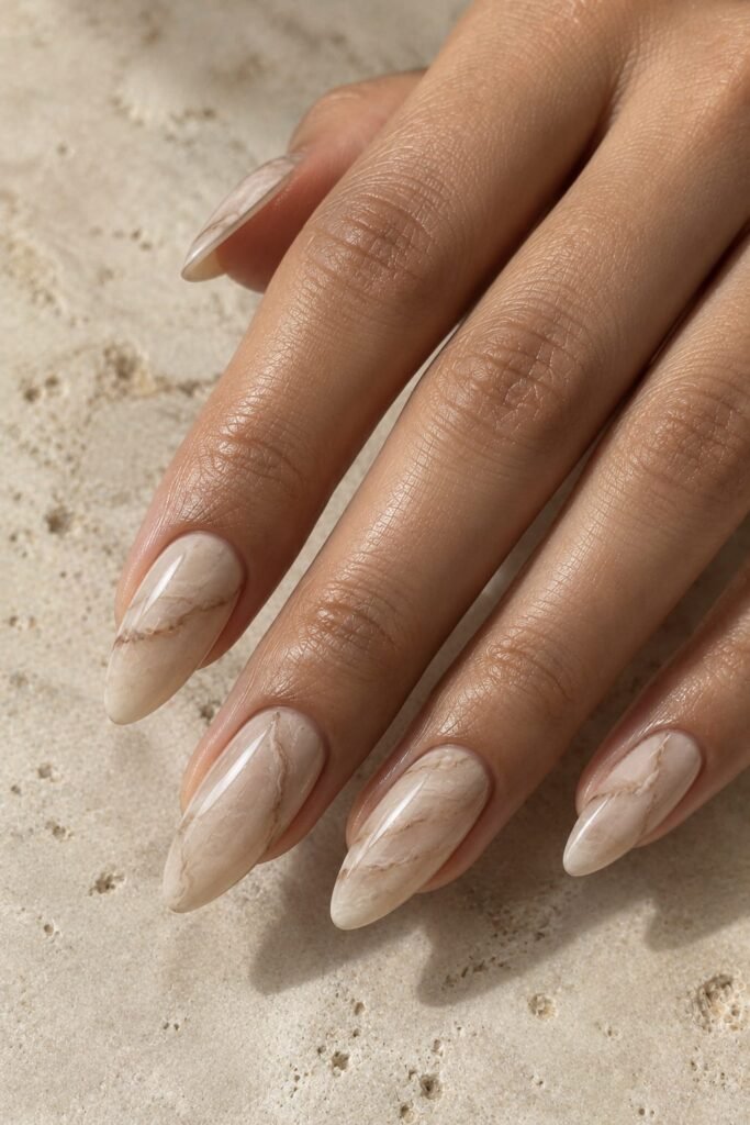 Warm beige almond nails with fine ivory and taupe marble veining