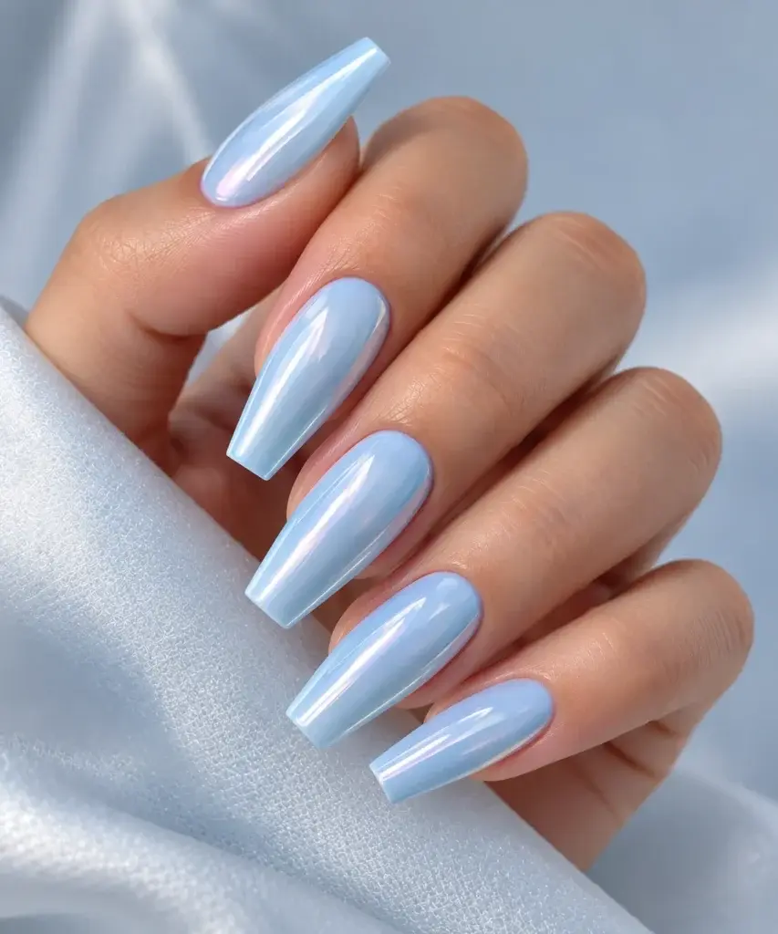 Close-up of long, almond-shaped nails painted in a glossy light blue shade, resting on a white textured fabric.