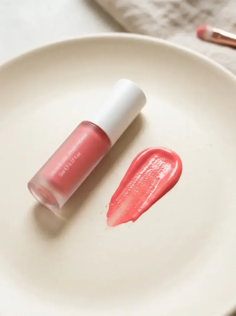 Pink liquid blush tube beside a fresh pink cosmetic swatch.